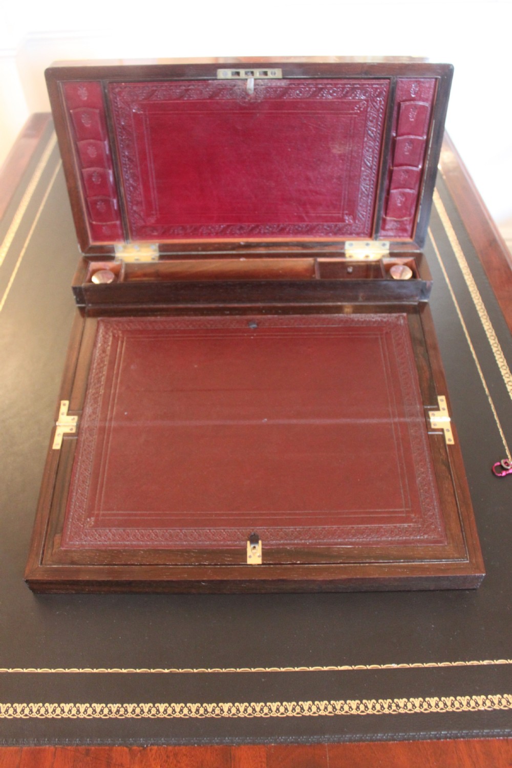 A rectangular dark rosewood writing slope box with brass corner mounts, brass cartouche inlay, and a central brass keyhole with a tassel. View IX