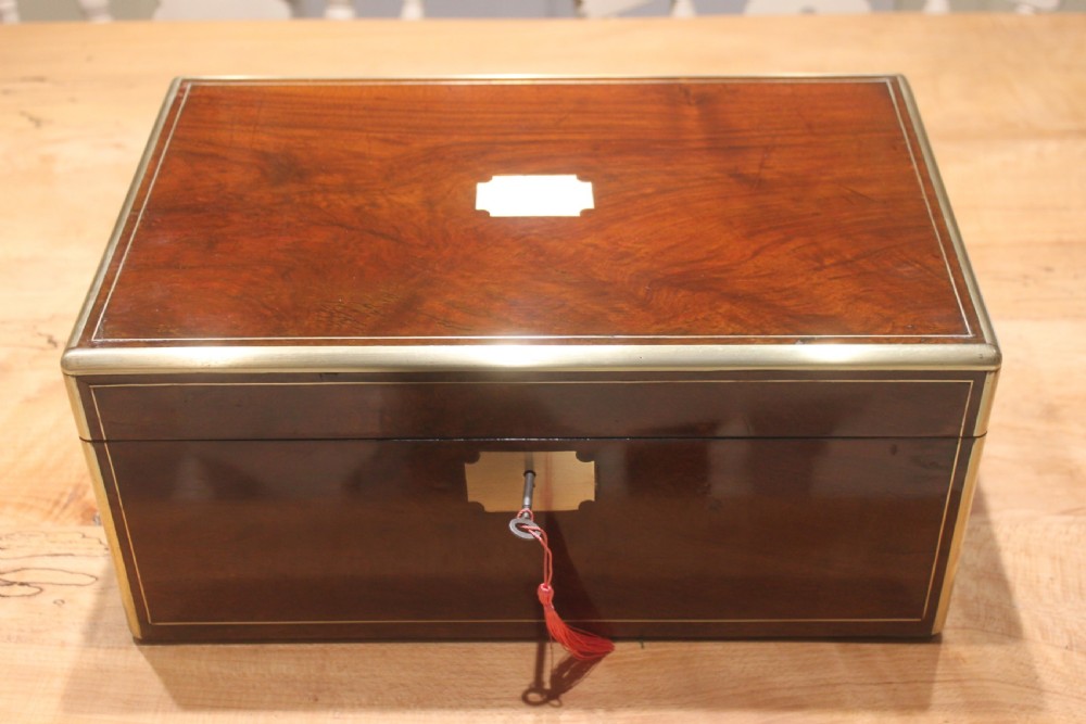 A dark walnut rectangular writing slope with brass edge binding, an inset brass plaque on top, and a brass escutcheon with key.