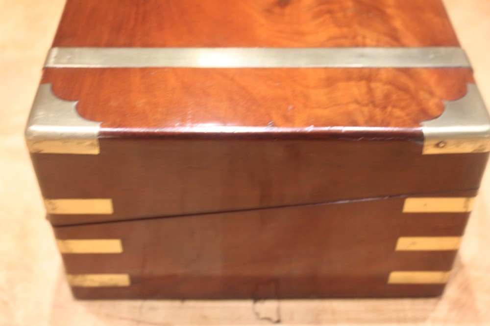 A closed mahogany campaign writing slope featuring brass corner brackets, brass banding, and a central brass cartouche with a key in the escutcheon. View II