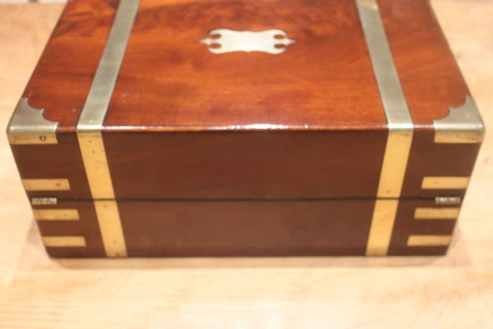 A closed mahogany campaign writing slope featuring brass corner brackets, brass banding, and a central brass cartouche with a key in the escutcheon. View III
