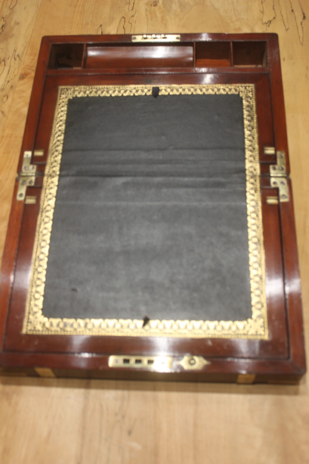 A closed mahogany campaign writing slope featuring brass corner brackets, brass banding, and a central brass cartouche with a key in the escutcheon. View VI