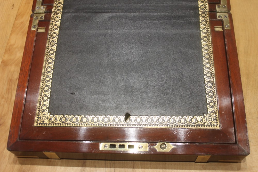 A closed mahogany campaign writing slope featuring brass corner brackets, brass banding, and a central brass cartouche with a key in the escutcheon. View VII