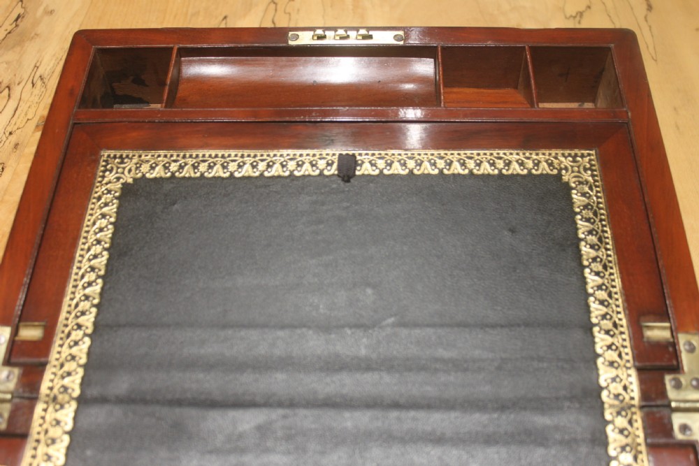 A closed mahogany campaign writing slope featuring brass corner brackets, brass banding, and a central brass cartouche with a key in the escutcheon. View VIII