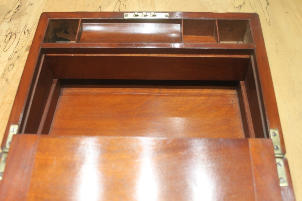 A closed mahogany campaign writing slope featuring brass corner brackets, brass banding, and a central brass cartouche with a key in the escutcheon. View X
