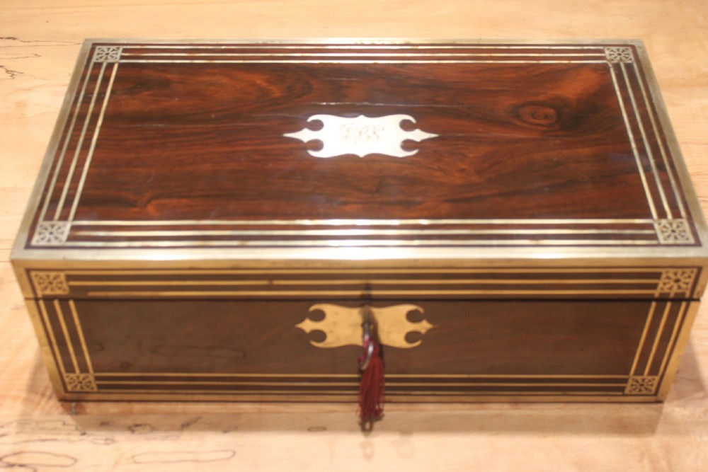 A late Georgian dark rosewood writing slope box decorated with geometric brass stringing, corner details, and a central brass cartouche.