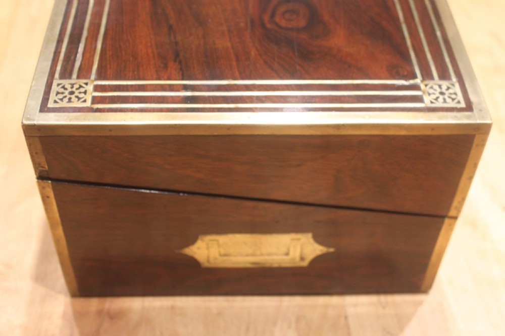 A late Georgian dark rosewood writing slope box decorated with geometric brass stringing, corner details, and a central brass cartouche. View V