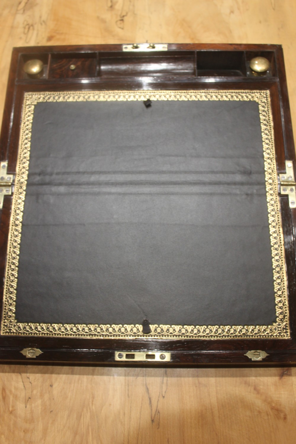 A late Georgian dark rosewood writing slope box decorated with geometric brass stringing, corner details, and a central brass cartouche. View VI