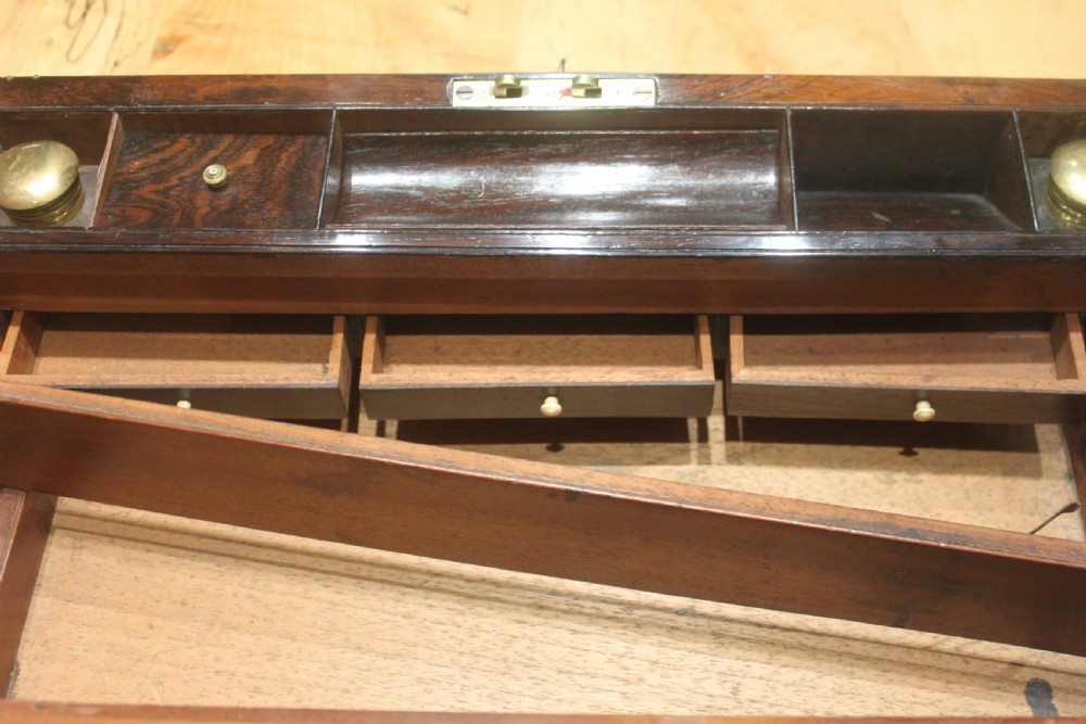 A late Georgian dark rosewood writing slope box decorated with geometric brass stringing, corner details, and a central brass cartouche. View XIII