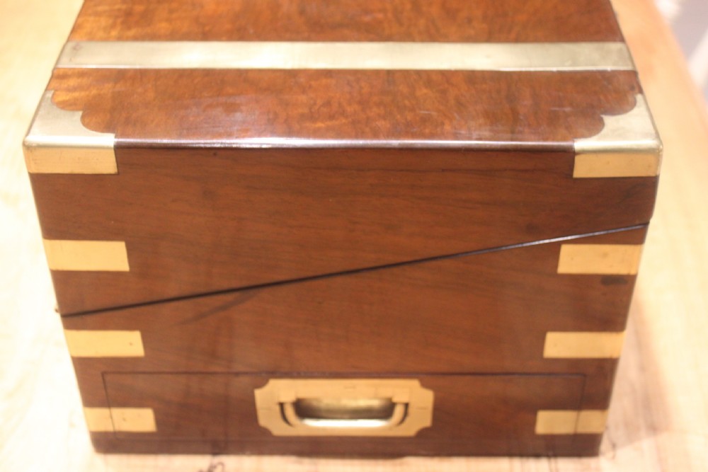 A rectangular figured walnut writing slope decorated with brass corner brackets, brass strapping, a blank central brass cartouche, and a keyhole escutcheon. View II
