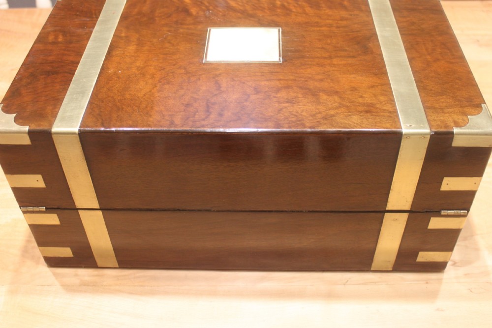 A rectangular figured walnut writing slope decorated with brass corner brackets, brass strapping, a blank central brass cartouche, and a keyhole escutcheon. View III