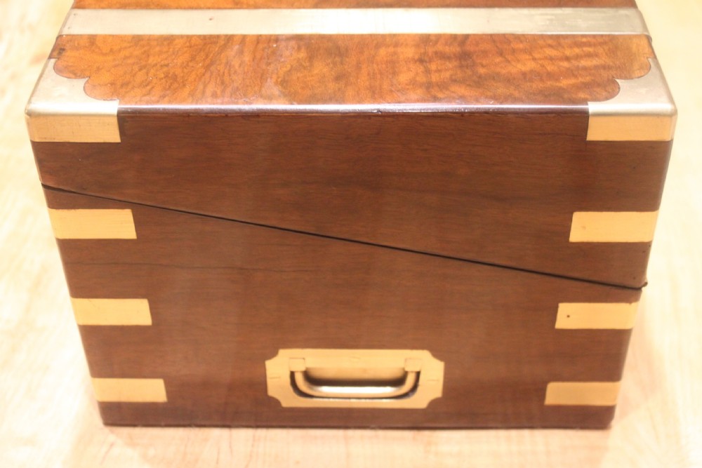 A rectangular figured walnut writing slope decorated with brass corner brackets, brass strapping, a blank central brass cartouche, and a keyhole escutcheon. View V