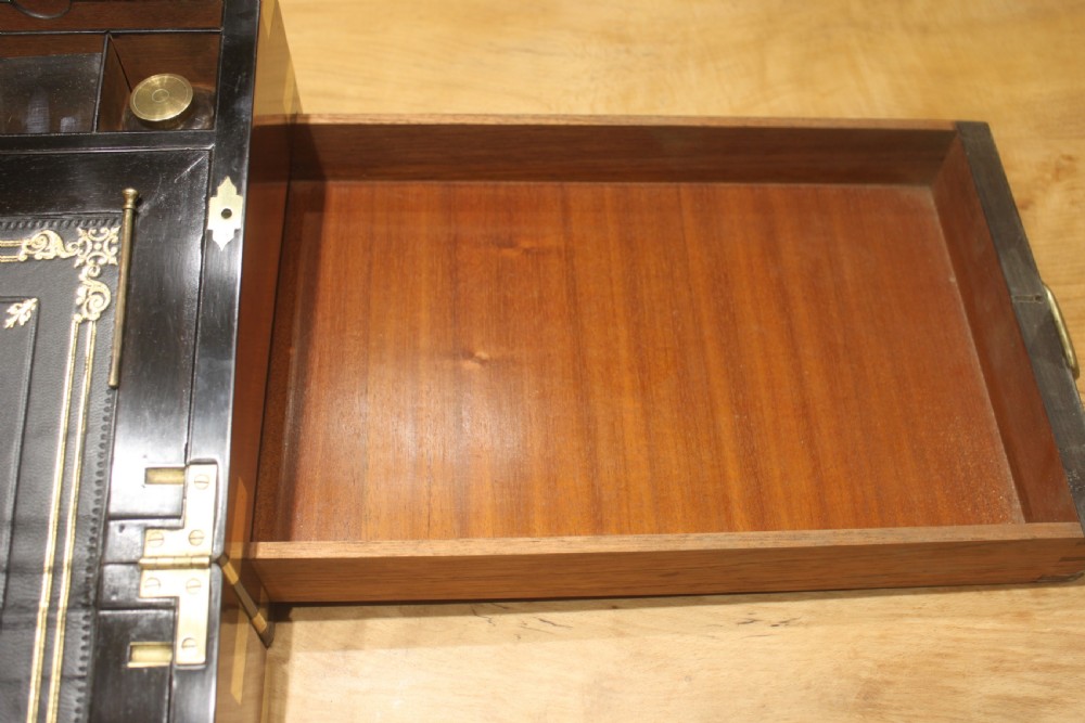 A rectangular figured walnut writing slope decorated with brass corner brackets, brass strapping, a blank central brass cartouche, and a keyhole escutcheon. View VII