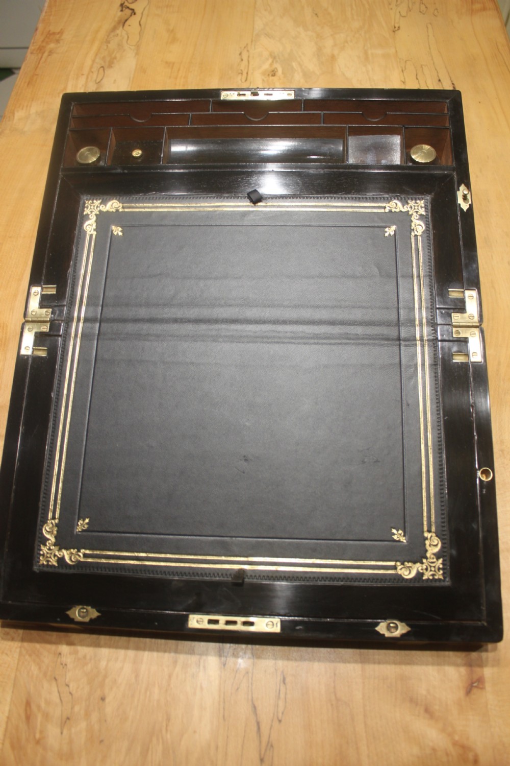 A rectangular figured walnut writing slope decorated with brass corner brackets, brass strapping, a blank central brass cartouche, and a keyhole escutcheon. View VIII