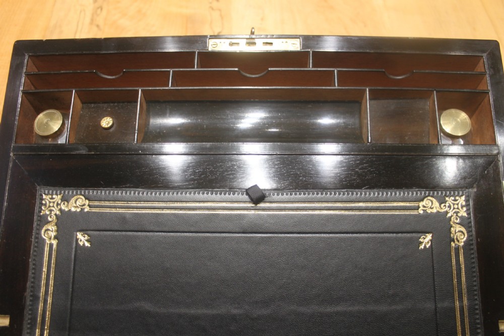A rectangular figured walnut writing slope decorated with brass corner brackets, brass strapping, a blank central brass cartouche, and a keyhole escutcheon. View IX