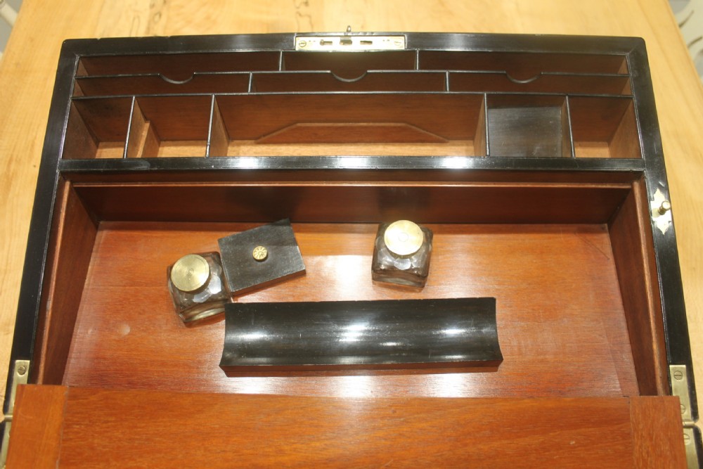 A rectangular figured walnut writing slope decorated with brass corner brackets, brass strapping, a blank central brass cartouche, and a keyhole escutcheon. View X