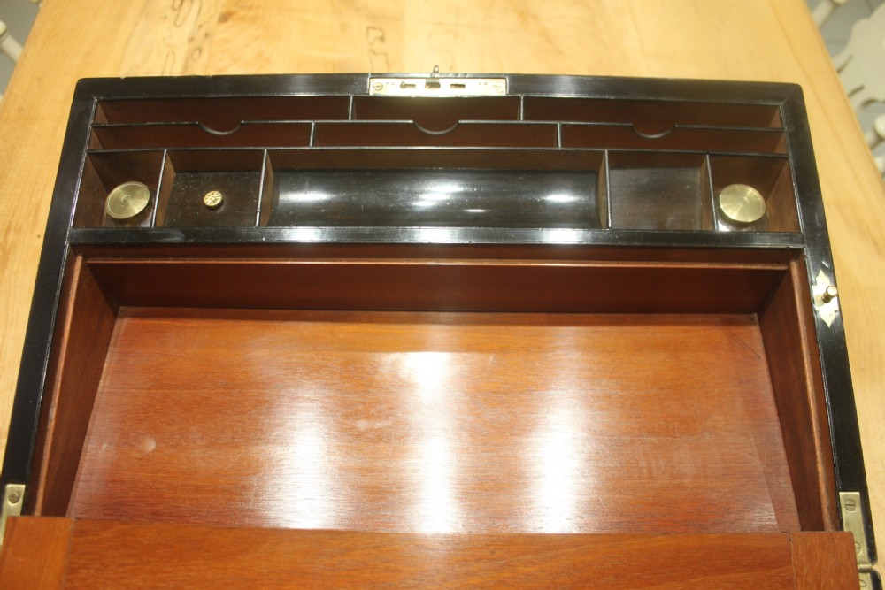 A rectangular figured walnut writing slope decorated with brass corner brackets, brass strapping, a blank central brass cartouche, and a keyhole escutcheon. View XI