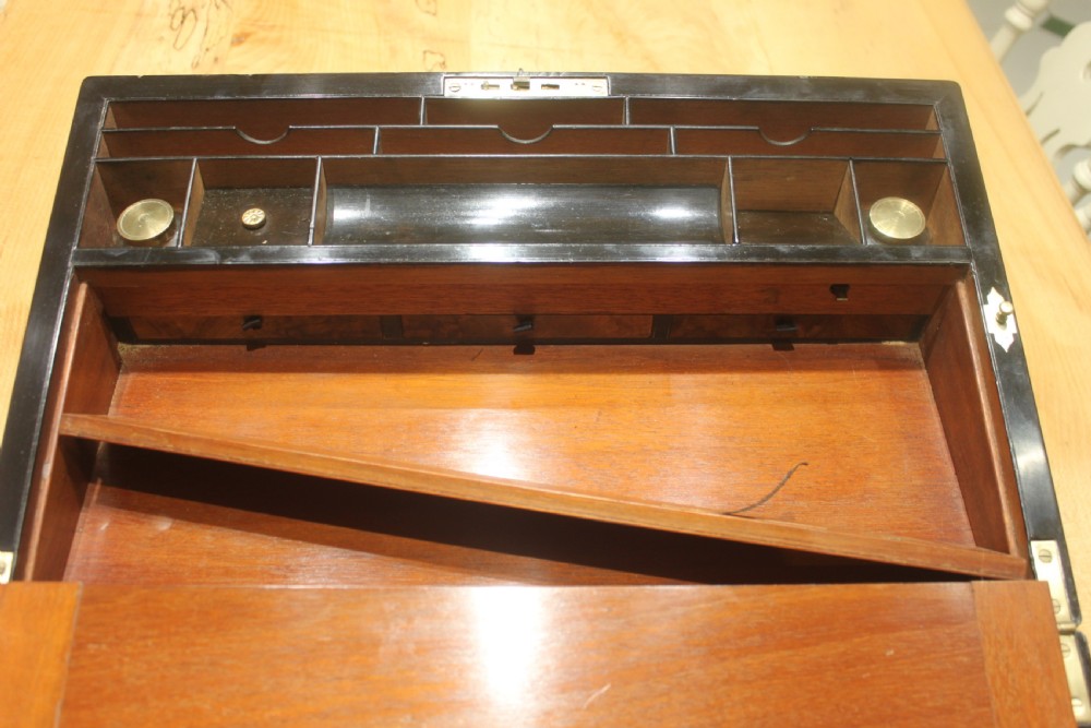 A rectangular figured walnut writing slope decorated with brass corner brackets, brass strapping, a blank central brass cartouche, and a keyhole escutcheon. View XII