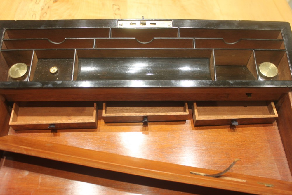 A rectangular figured walnut writing slope decorated with brass corner brackets, brass strapping, a blank central brass cartouche, and a keyhole escutcheon. View XIII