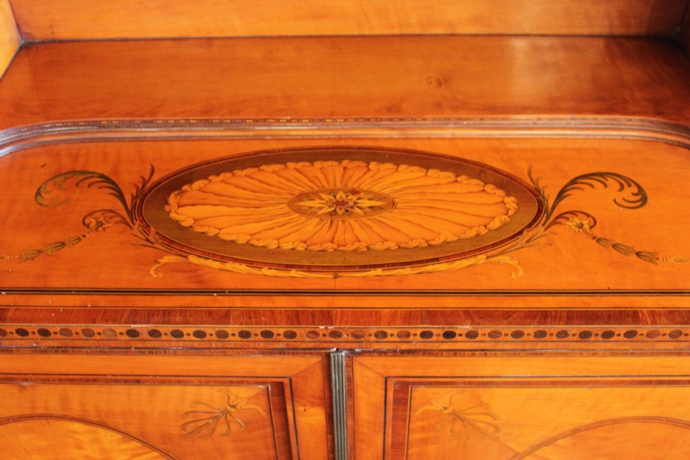 An antique Sheraton style satinwood cabinet with an open tiered shelving top unit and a lower two-door cabinet featuring oval inlaid marquetry panels. View V