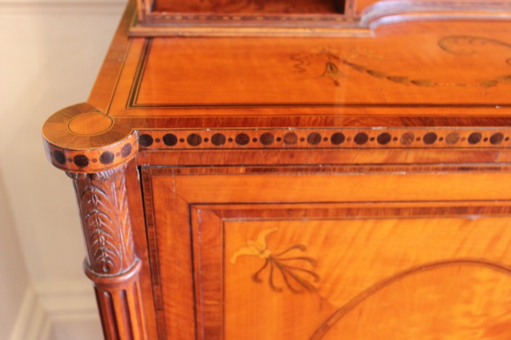 An antique Sheraton style satinwood cabinet with an open tiered shelving top unit and a lower two-door cabinet featuring oval inlaid marquetry panels. View VI