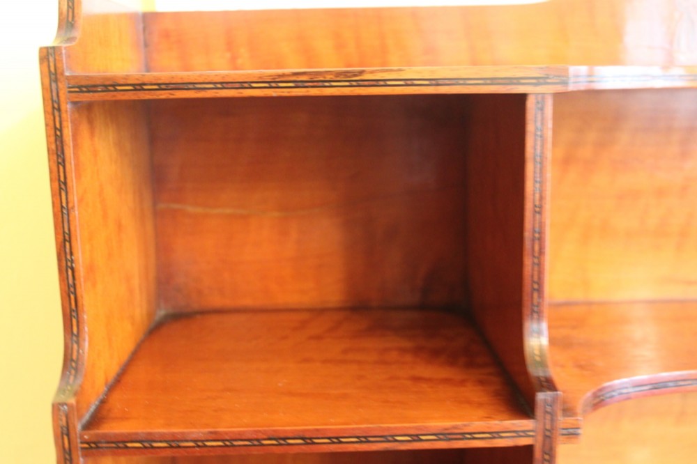 An antique Sheraton style satinwood cabinet with an open tiered shelving top unit and a lower two-door cabinet featuring oval inlaid marquetry panels. View VII