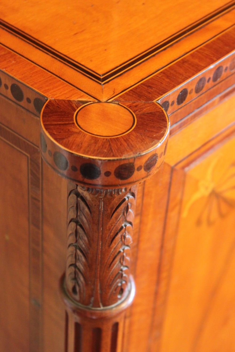 An antique Sheraton style satinwood cabinet with an open tiered shelving top unit and a lower two-door cabinet featuring oval inlaid marquetry panels. View IX