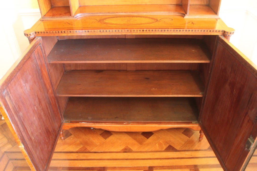 An antique Sheraton style satinwood cabinet with an open tiered shelving top unit and a lower two-door cabinet featuring oval inlaid marquetry panels. View XI
