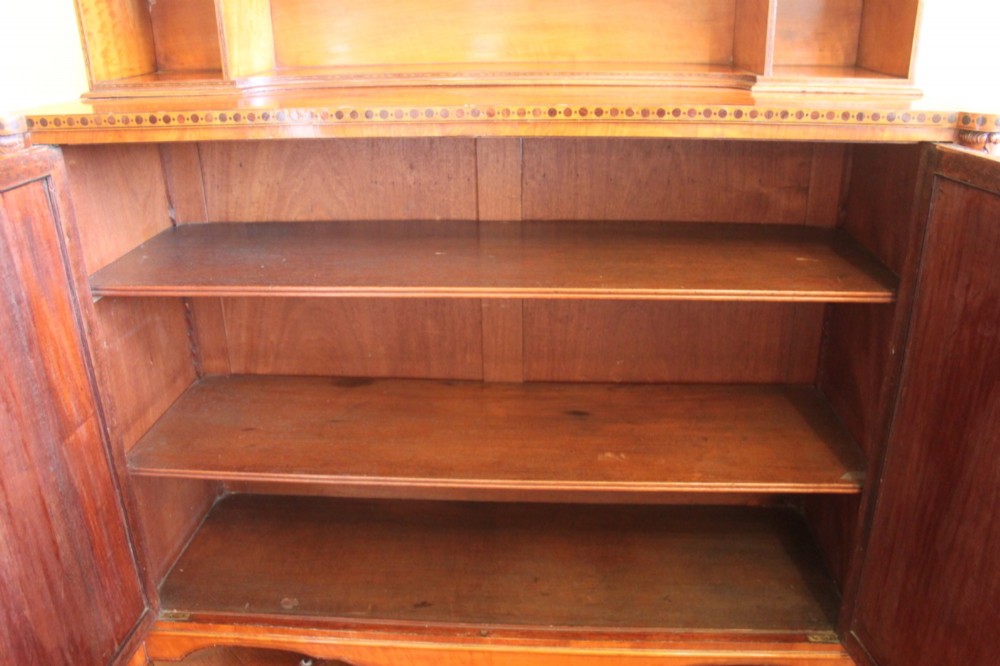An antique Sheraton style satinwood cabinet with an open tiered shelving top unit and a lower two-door cabinet featuring oval inlaid marquetry panels. View XIII