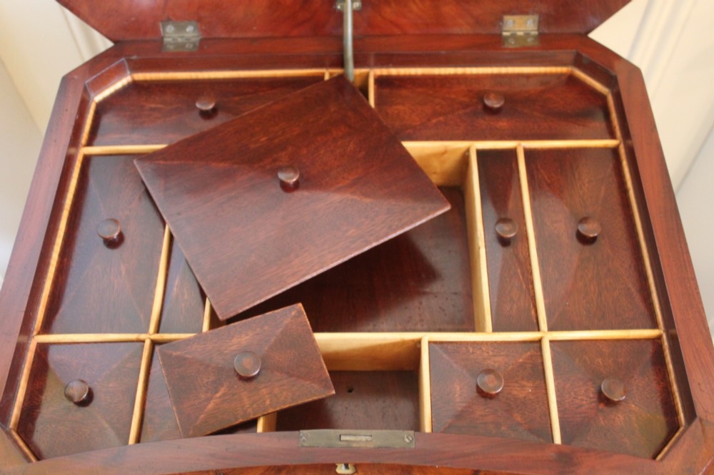 An early Victorian flame mahogany work table featuring a hinged top, carved central pedestal, triform base, and carved lion paw feet. View VI