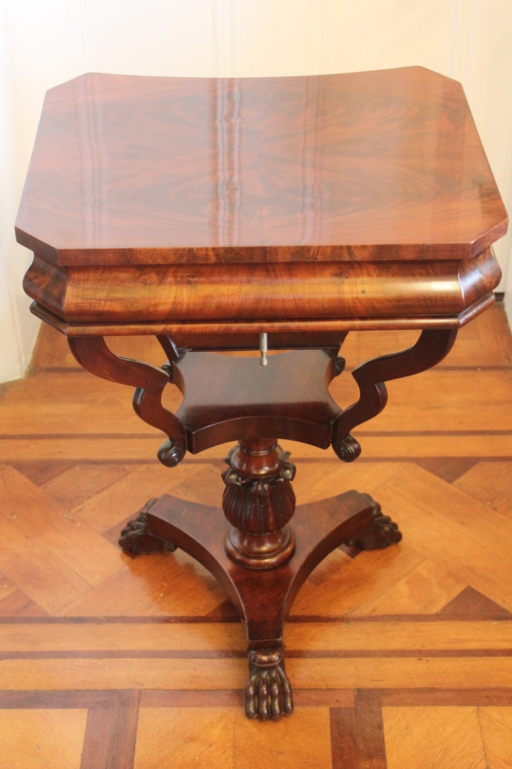An early Victorian flame mahogany work table featuring a hinged top, carved central pedestal, triform base, and carved lion paw feet. View IX