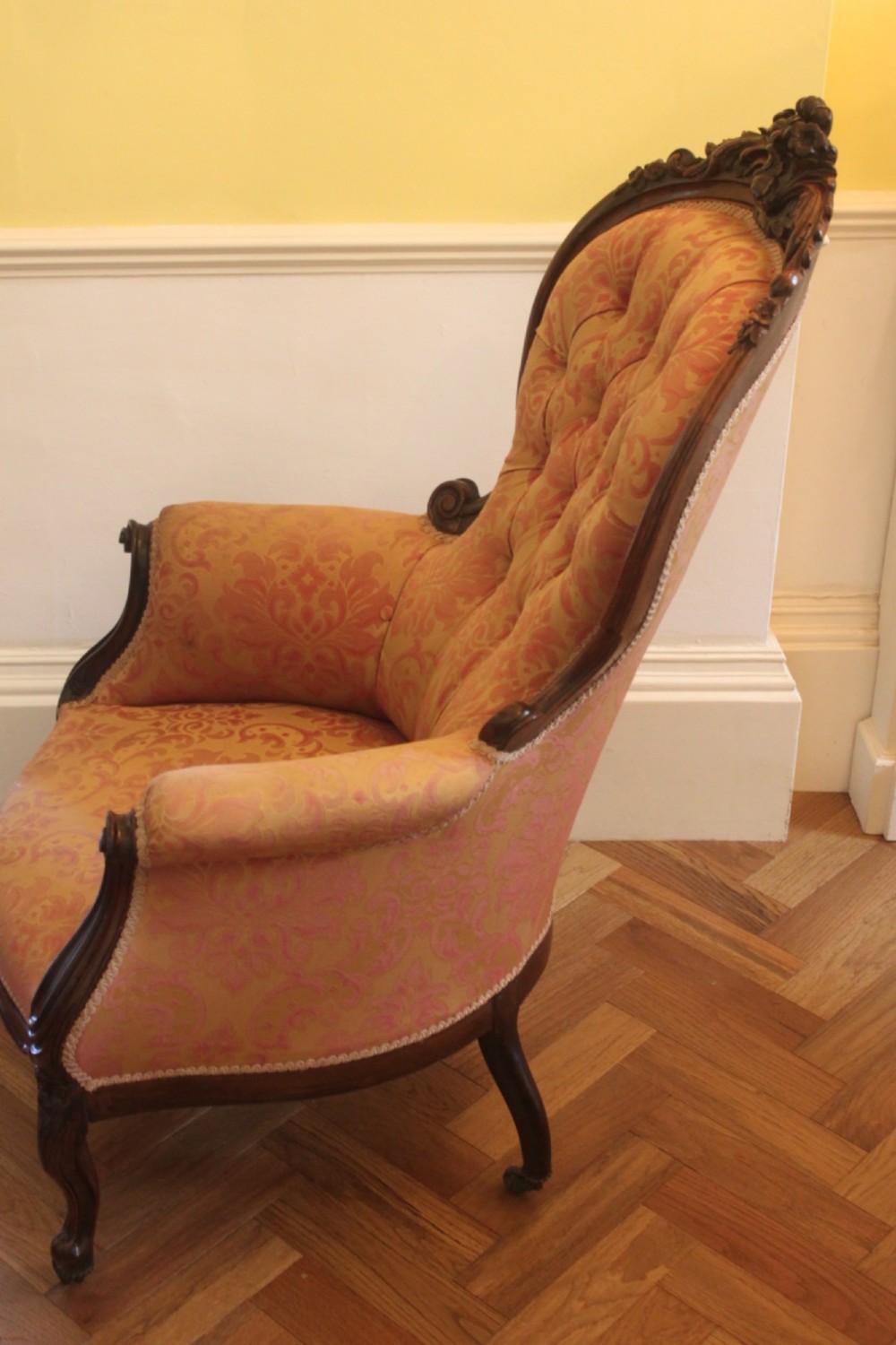 An early Victorian balloon-back gentlemans armchair with a carved dark mahogany frame, button-backed yellow damask upholstery, and cabriole legs. View II