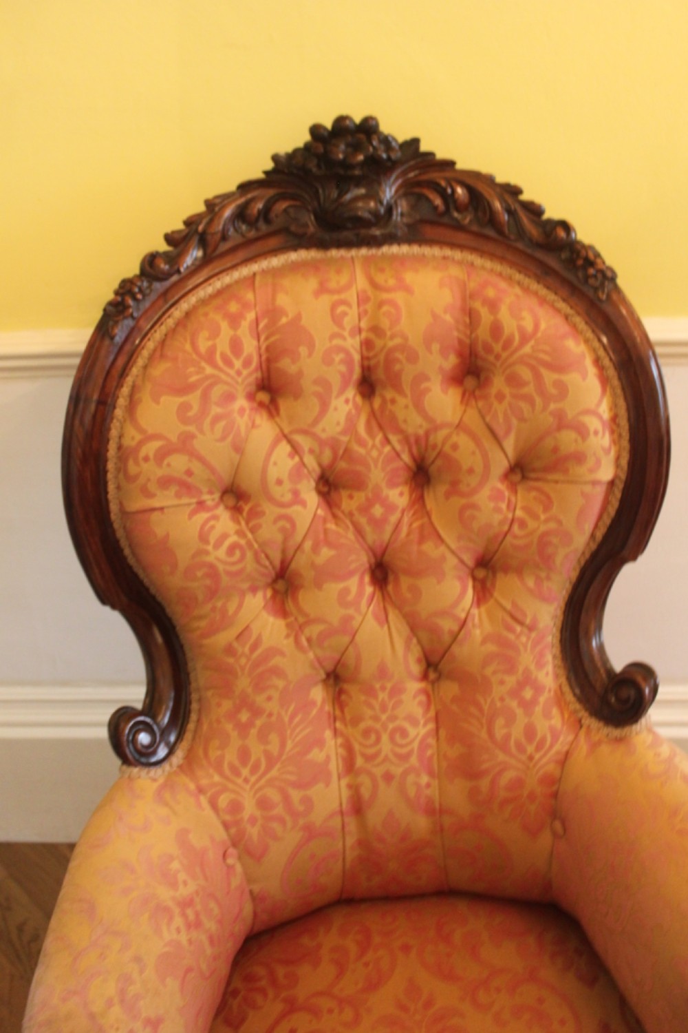 An early Victorian balloon-back gentlemans armchair with a carved dark mahogany frame, button-backed yellow damask upholstery, and cabriole legs. View V