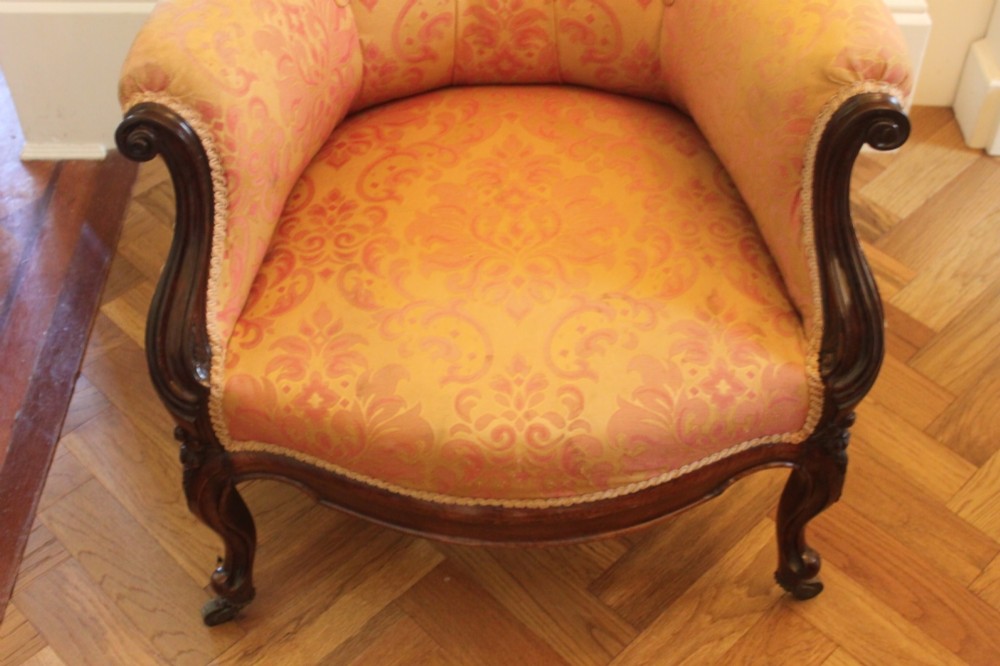 An early Victorian balloon-back gentlemans armchair with a carved dark mahogany frame, button-backed yellow damask upholstery, and cabriole legs. View VI