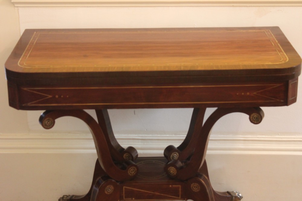 A Regency mahogany fold-over card table featuring geometric brass inlay, scroll supports, and brass paw feet on castors. View II
