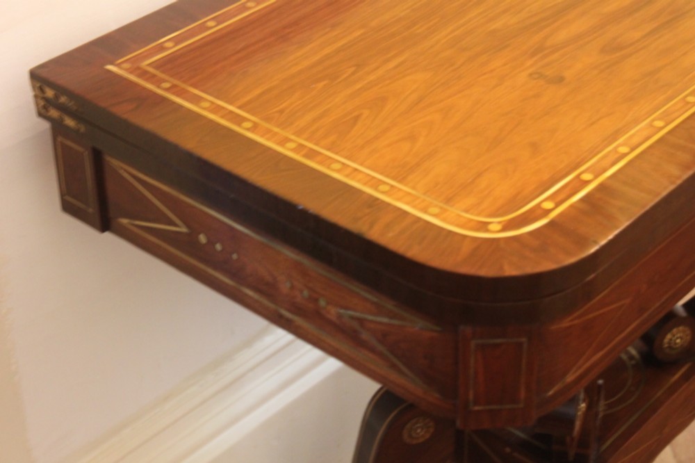 A Regency mahogany fold-over card table featuring geometric brass inlay, scroll supports, and brass paw feet on castors. View V