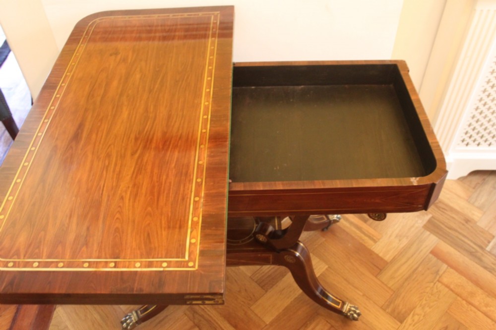 A Regency mahogany fold-over card table featuring geometric brass inlay, scroll supports, and brass paw feet on castors. View VII