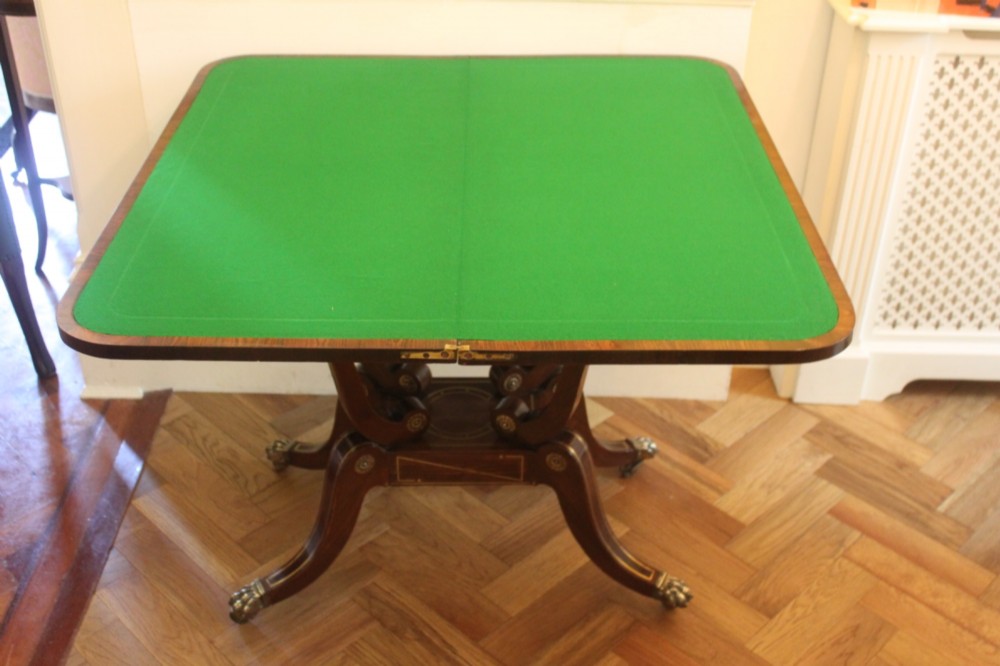 A Regency mahogany fold-over card table featuring geometric brass inlay, scroll supports, and brass paw feet on castors. View VIII