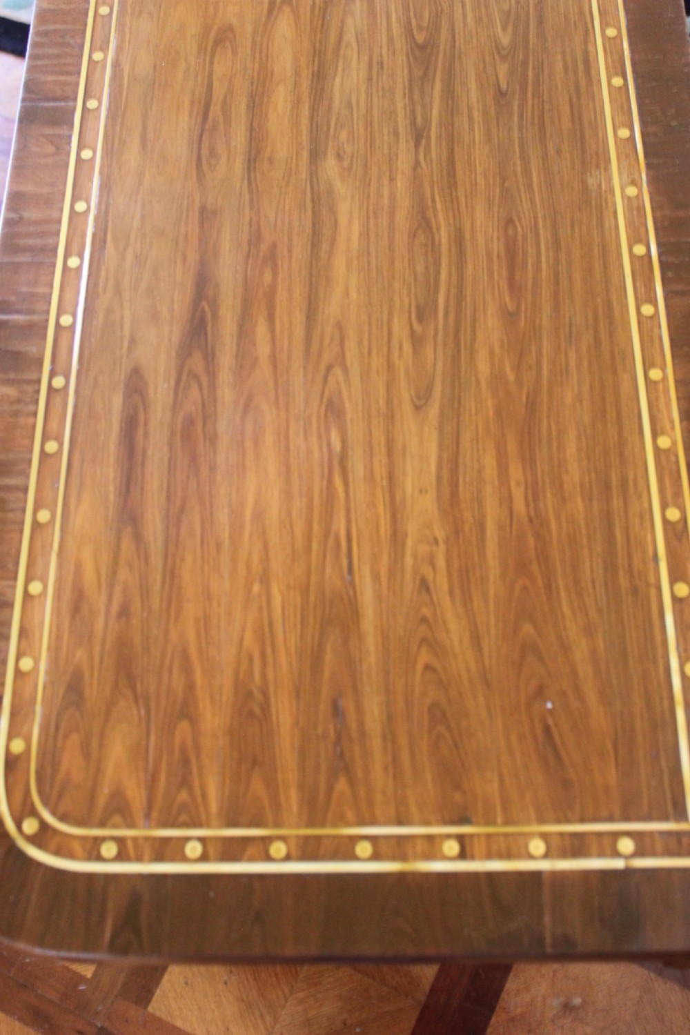 A Regency mahogany fold-over card table featuring geometric brass inlay, scroll supports, and brass paw feet on castors. View X