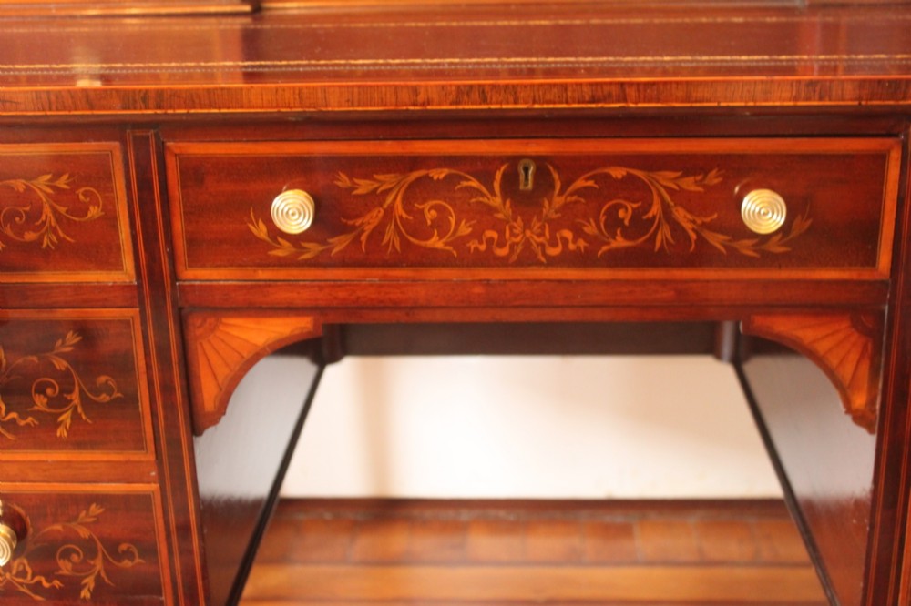 A Sheraton Revival mahogany writing desk featuring intricate marquetry inlays, a brown leather writing surface, a raised superstructure with small drawers, and square tapered legs. View III