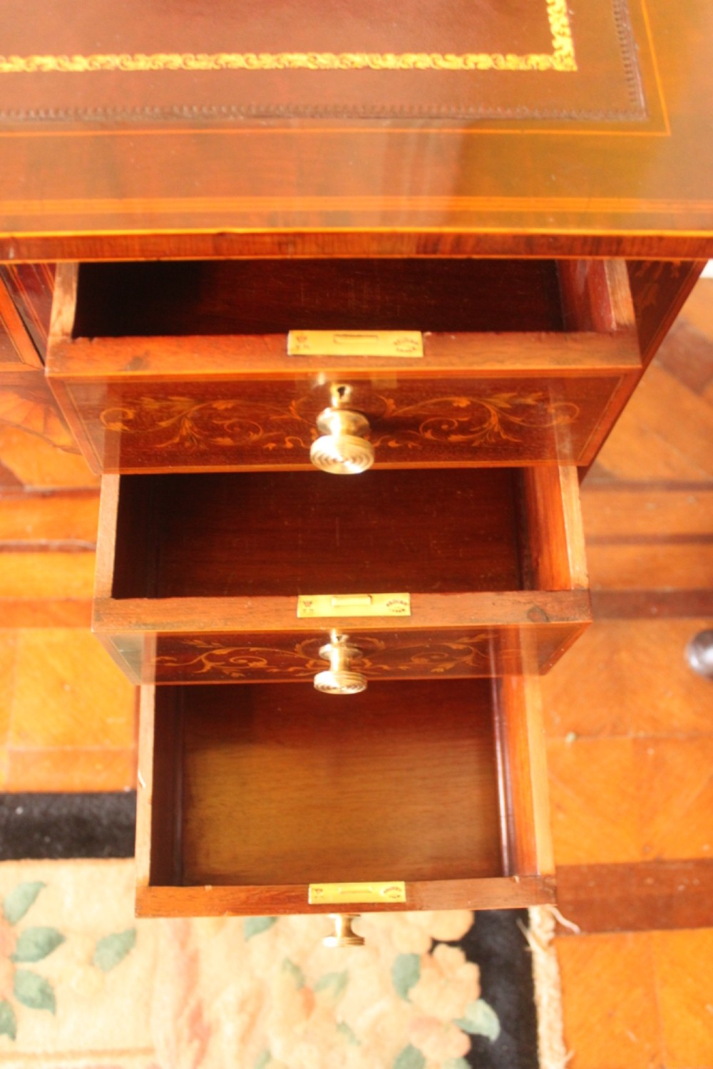 A Sheraton Revival mahogany writing desk featuring intricate marquetry inlays, a brown leather writing surface, a raised superstructure with small drawers, and square tapered legs. View V