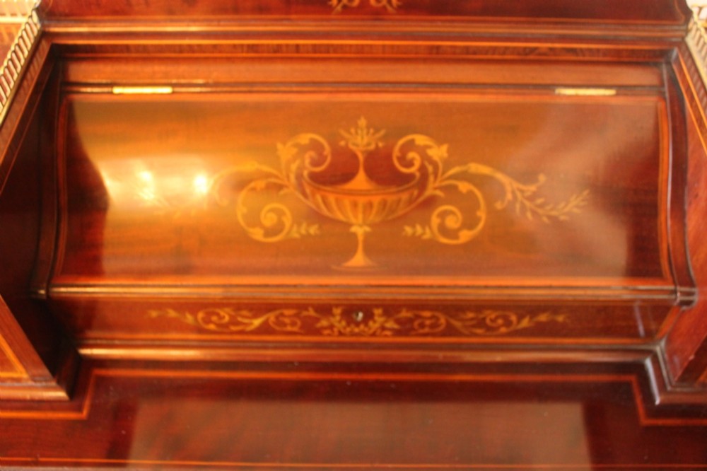 A Sheraton Revival mahogany writing desk featuring intricate marquetry inlays, a brown leather writing surface, a raised superstructure with small drawers, and square tapered legs. View VIII