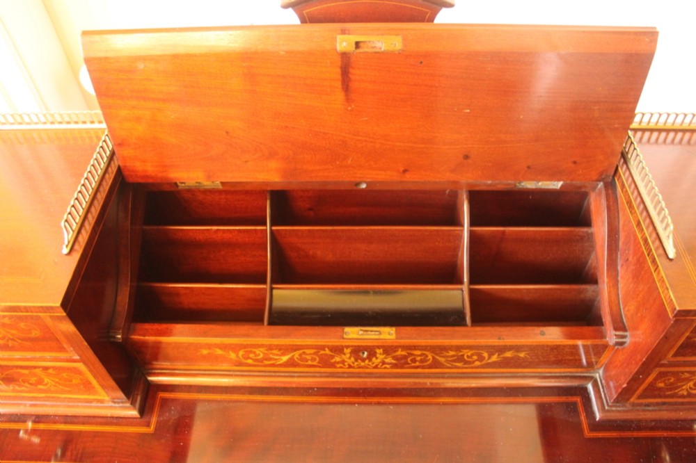 A Sheraton Revival mahogany writing desk featuring intricate marquetry inlays, a brown leather writing surface, a raised superstructure with small drawers, and square tapered legs. View IX