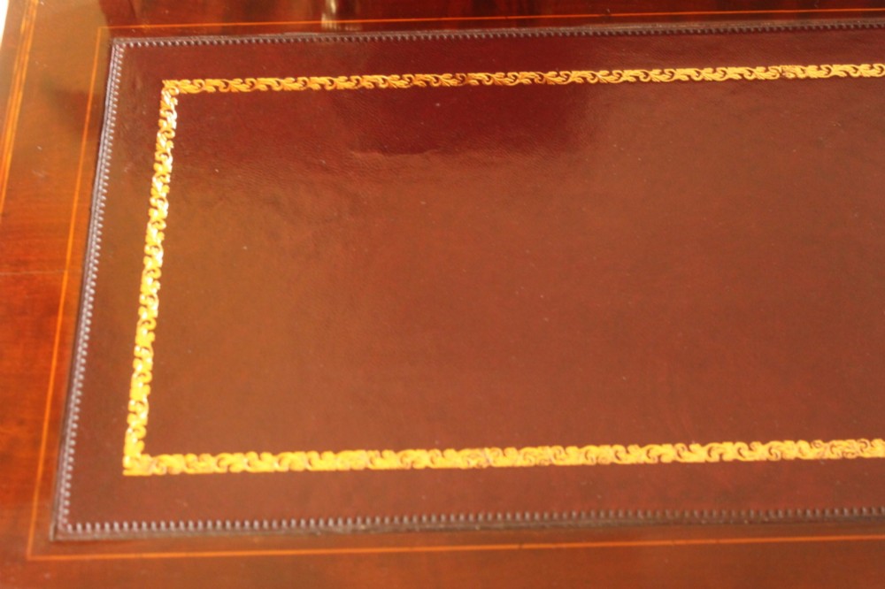 A Sheraton Revival mahogany writing desk featuring intricate marquetry inlays, a brown leather writing surface, a raised superstructure with small drawers, and square tapered legs. View XI