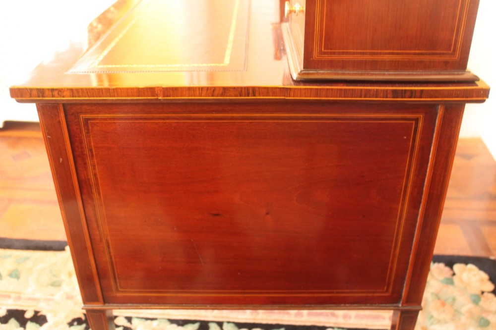 A Sheraton Revival mahogany writing desk featuring intricate marquetry inlays, a brown leather writing surface, a raised superstructure with small drawers, and square tapered legs. View XII
