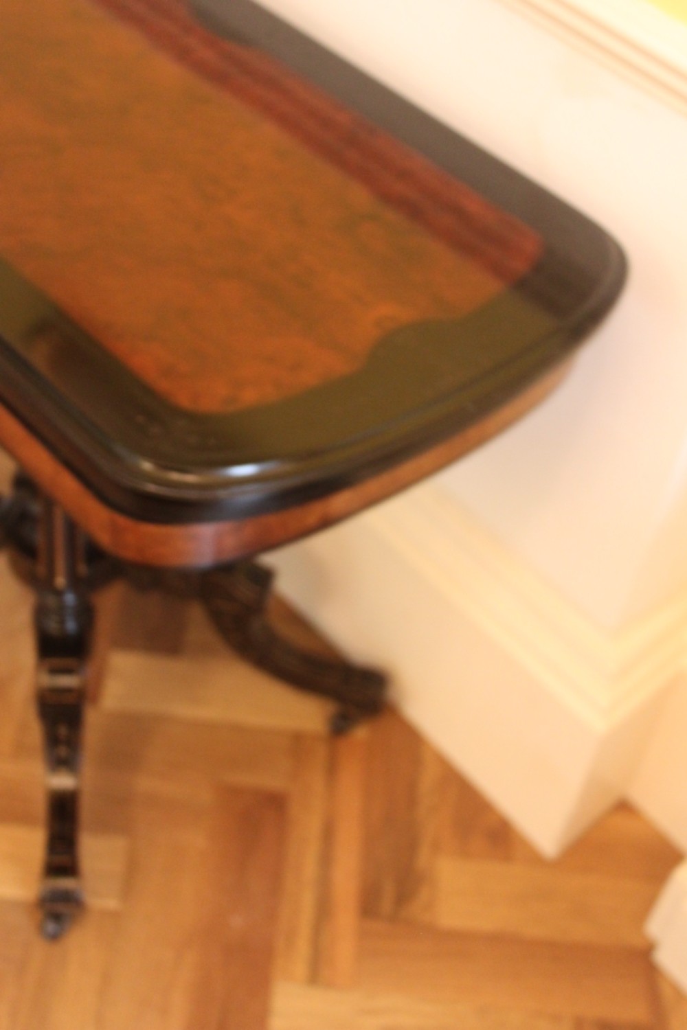 A Victorian foldover card table featuring a burr walnut top, ebonised border, double twin-column pedestal, and carved legs with castors. View II