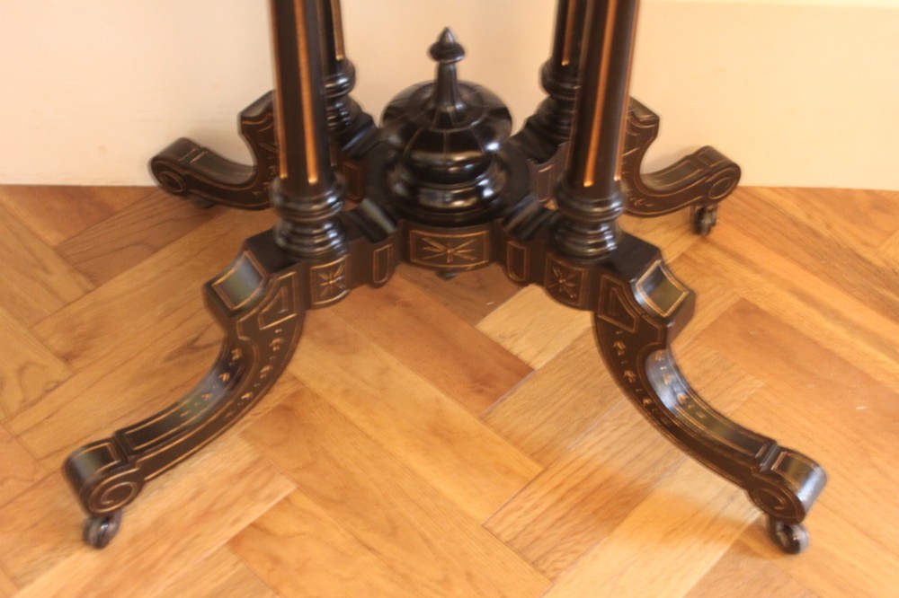 A Victorian foldover card table featuring a burr walnut top, ebonised border, double twin-column pedestal, and carved legs with castors. View VI