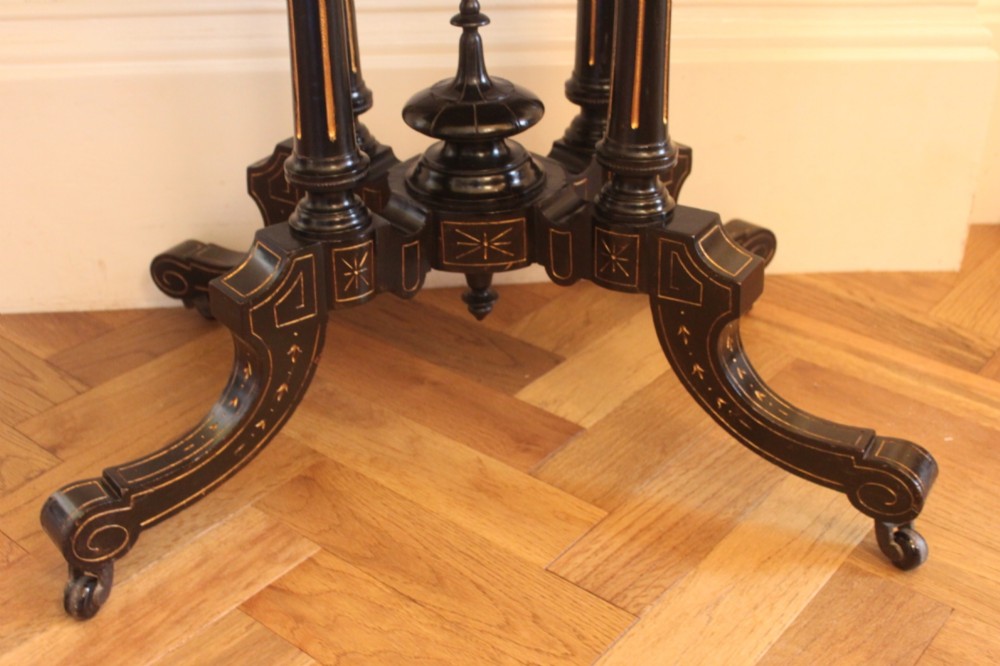 A Victorian foldover card table featuring a burr walnut top, ebonised border, double twin-column pedestal, and carved legs with castors. View VII