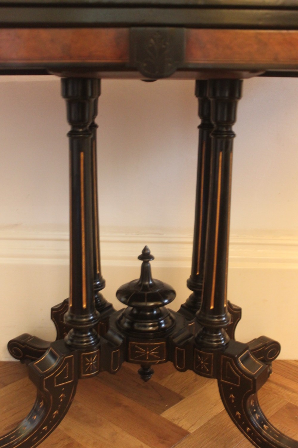 A Victorian foldover card table featuring a burr walnut top, ebonised border, double twin-column pedestal, and carved legs with castors. View VIII