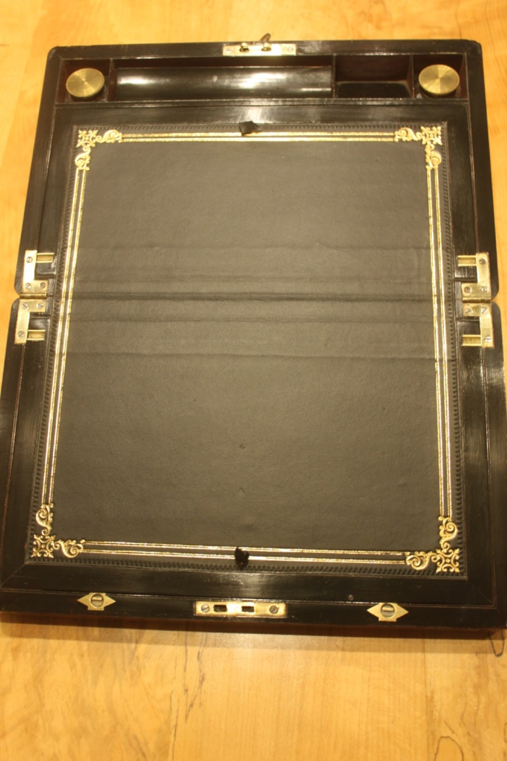A rectangular curl grain mahogany writing slope box featuring fine brass stringing, brass bound corners, a central brass cartouche, and a keyhole escutcheon. View VI