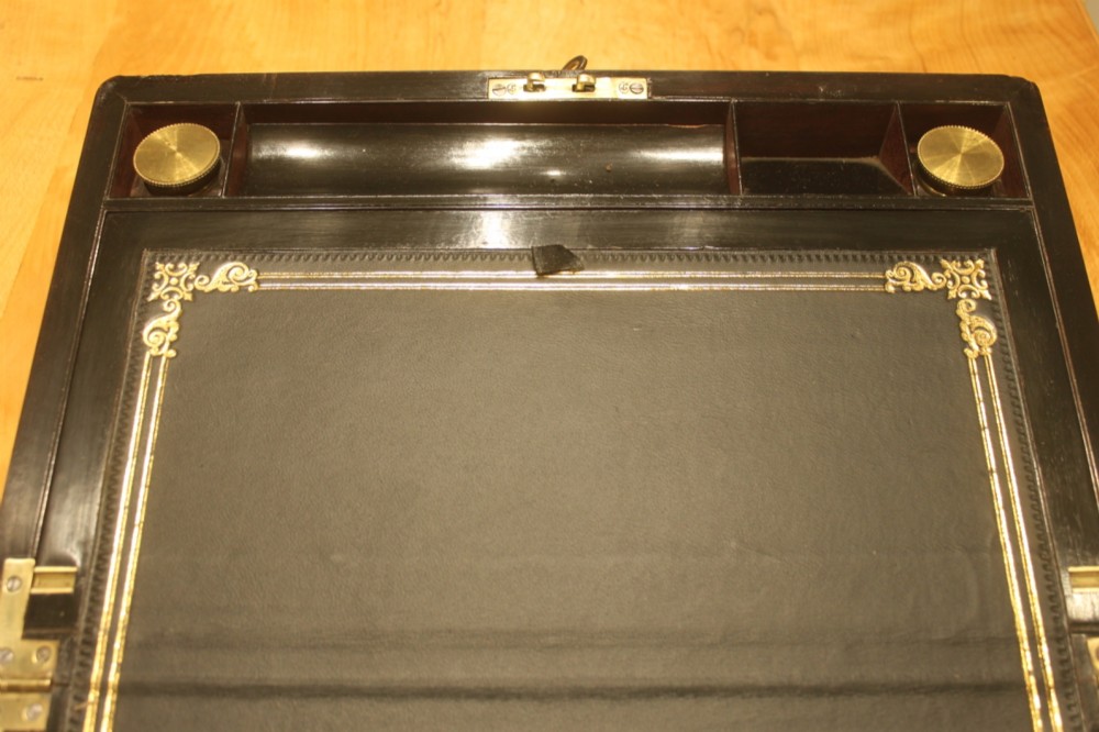 A rectangular curl grain mahogany writing slope box featuring fine brass stringing, brass bound corners, a central brass cartouche, and a keyhole escutcheon. View VIII
